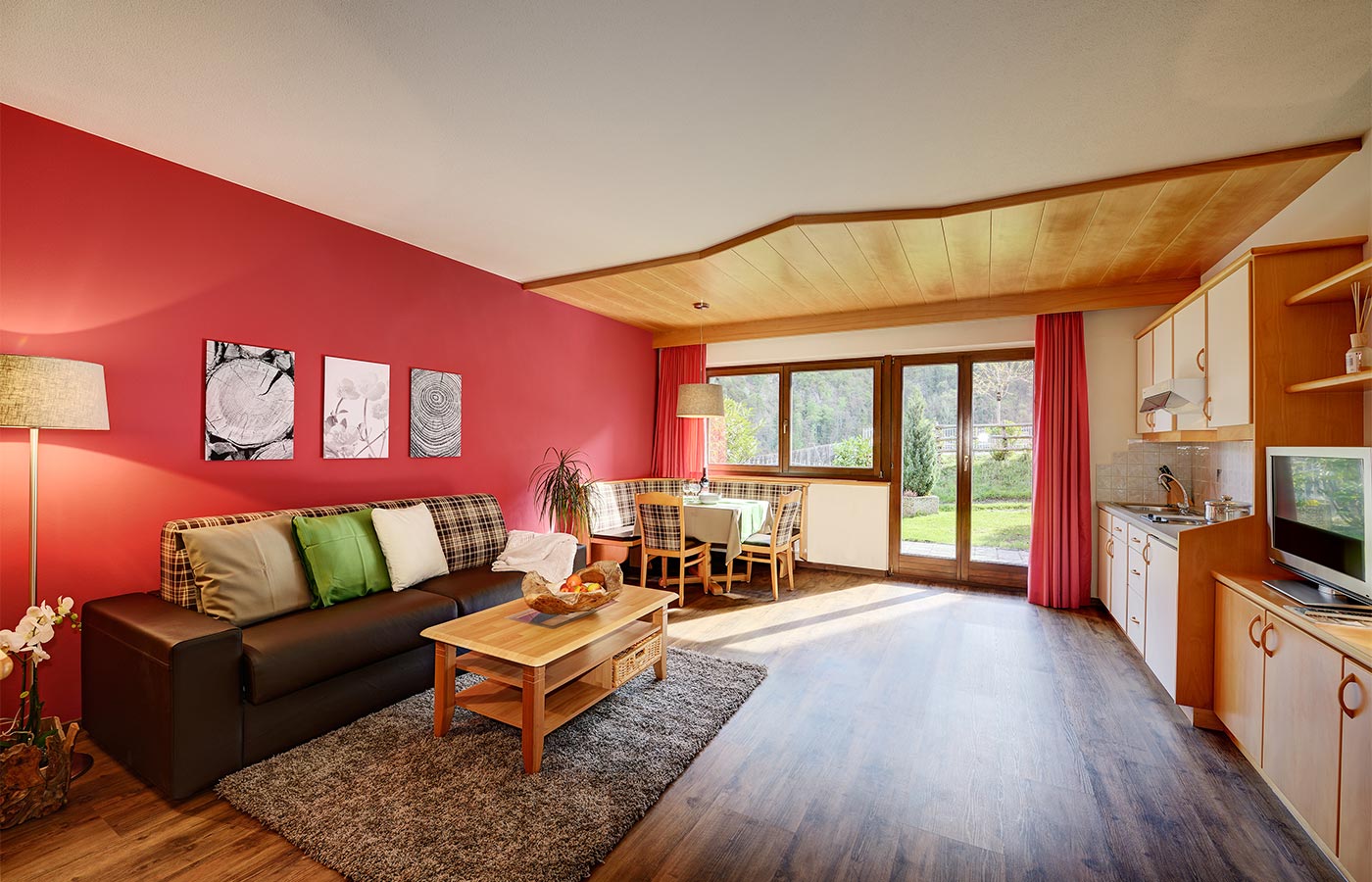 Ferienwohnung im Hotel Alpenhof mit rot gestrichener Wand und Holzboden