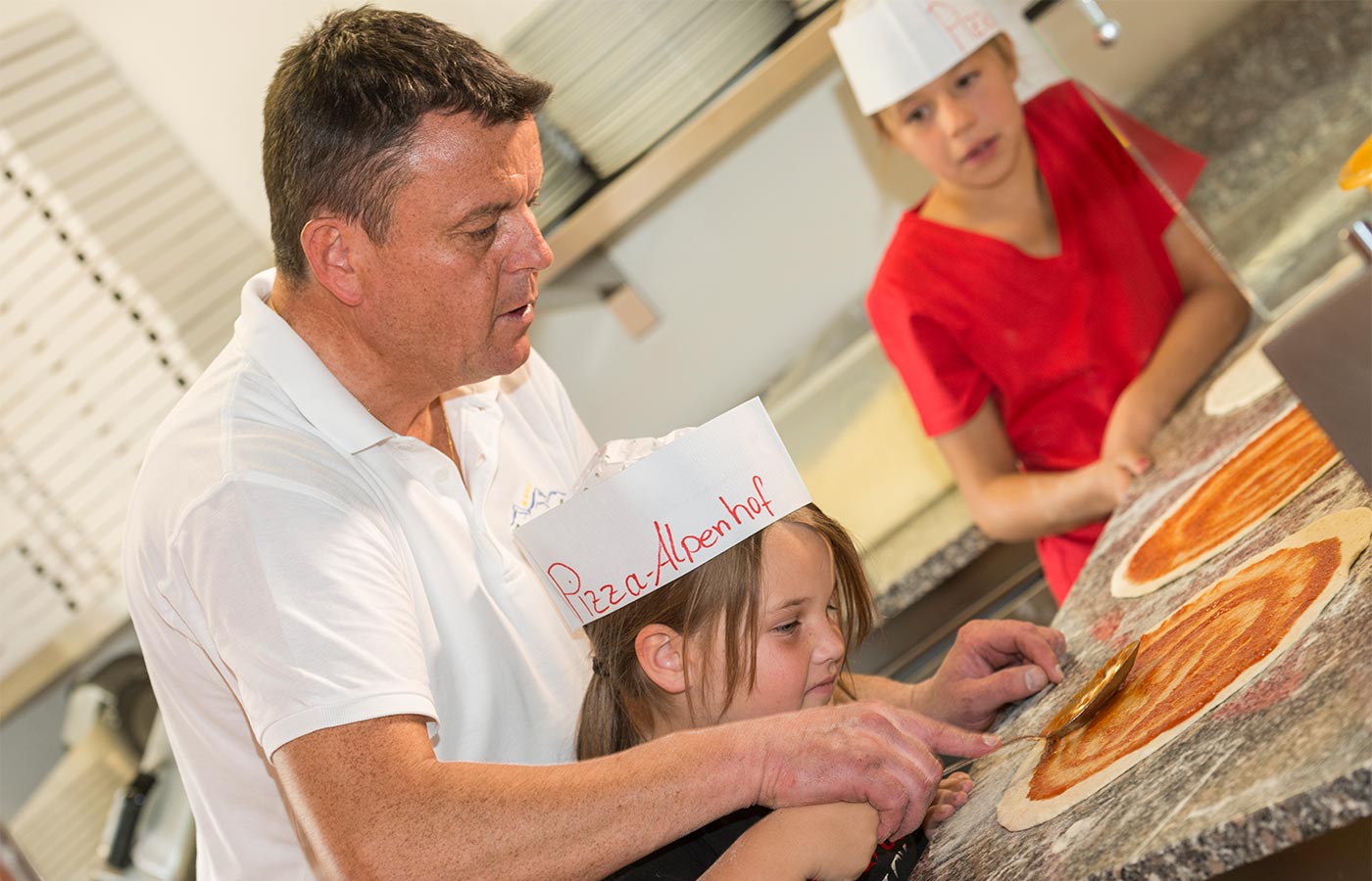 Der Hausherr des Hotel Alpenhof beim Pizzabacken mit Kindern in der Küche des Hotels
