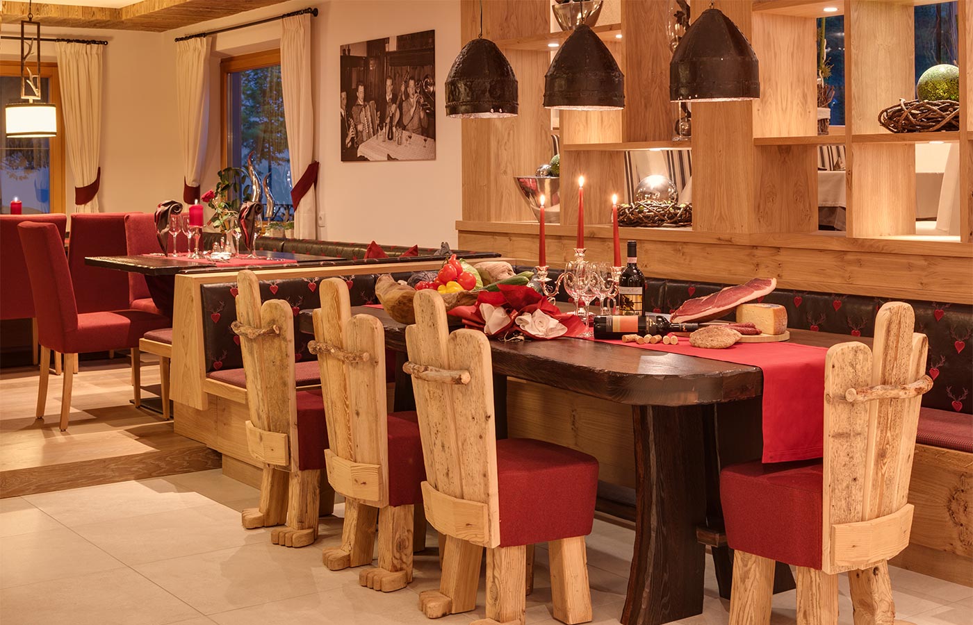 Großer gedeckter Tisch aus dunklem Holz mit rotem eleganten Läufer, Kerzen und kalter Platte