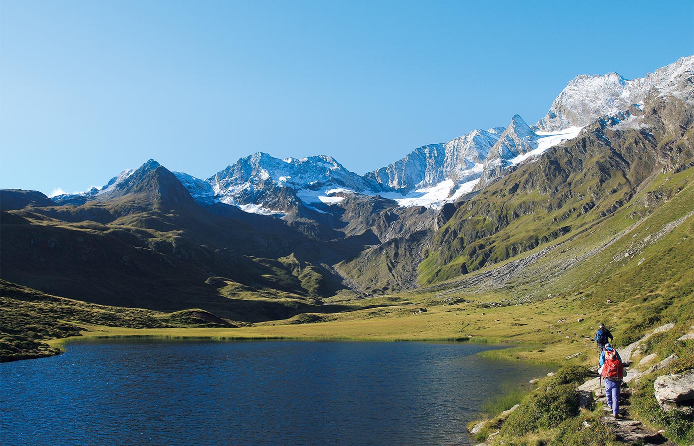 Bergsee und Wanderer an einem fast wolkenlosen Sommertag