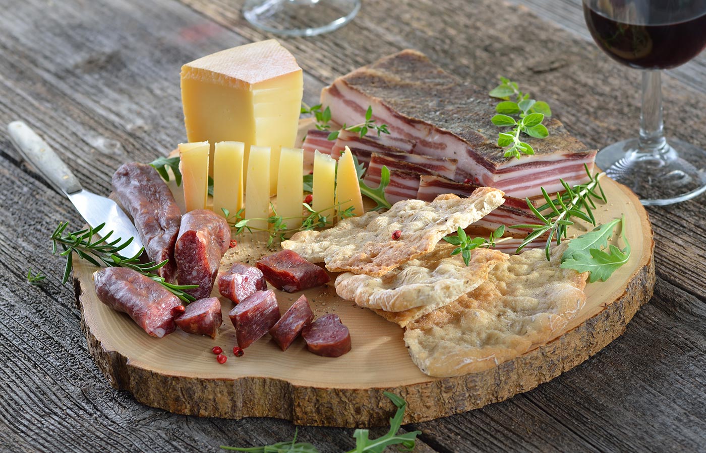 Rustikales Holzbrett mit Käse, Kaminwurzen, Speck und Schüttelbrot