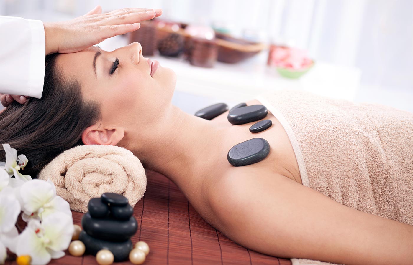 Dame bei einer Hot Stone Behandlung im Wellnessbereich des Hotel Alpenhof im Passeiertal